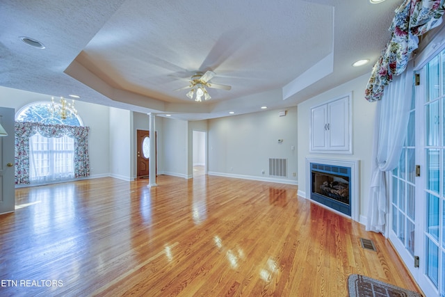 2150 Hirst Cir, Lenoir City, TN 37771 - unfurnished living room featuring a raised ceiling, a fireplace, a ceiling fan, light wood-style floors, and a textured ceiling