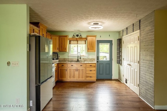 4148 New Home Rd, Smithville, TN 37166 - kitchen with freestanding refrigerator, a textured ceiling, dark wood-style flooring, brick wall, and light stone countertops