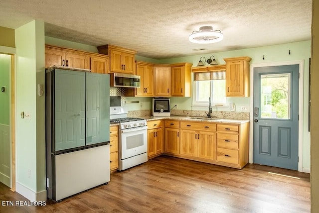 4148 New Home Rd, Smithville, TN 37166 - kitchen with white range with gas cooktop, stainless steel microwave, refrigerator, wood finished floors, and a textured ceiling