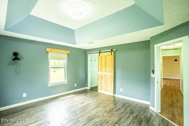 4148 New Home Rd, Smithville, TN 37166 - unfurnished bedroom featuring a tray ceiling, a barn door, and wood finished floors