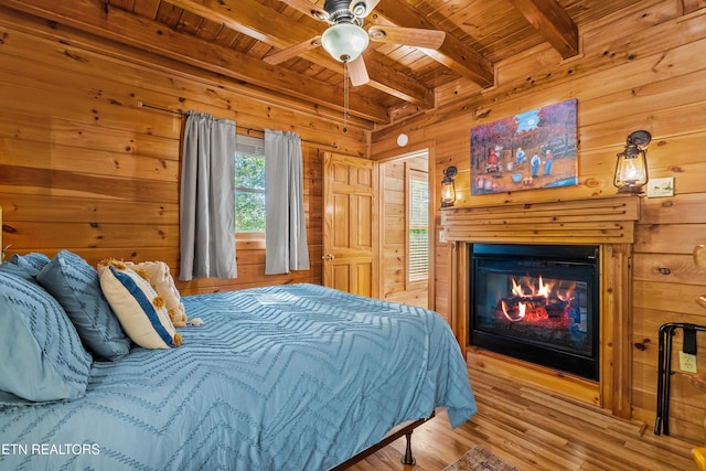 2011 Ridgecrest Loop Ln, Sevierville, TN 37876 - bedroom featuring a wooden ceiling with exposed beams, wooden walls, wood finished floors, a glass covered fireplace, and ceiling fan