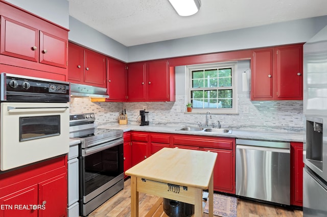 898 W Cunningham St, Alcoa, TN 37701 - kitchen with appliances with stainless steel finishes, red cabinets, under cabinet range hood, light countertops, and tasteful backsplash