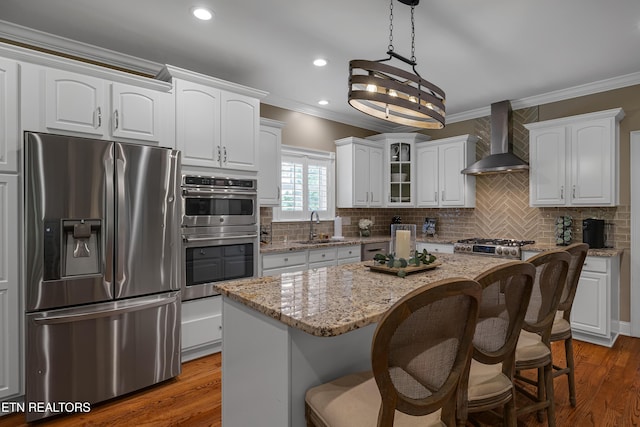 920 Andover View Ln, Knoxville, TN 37922 - kitchen featuring stainless steel appliances, wall chimney exhaust hood, ornamental molding, a kitchen island, and white cabinetry