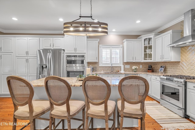 920 Andover View Ln, Knoxville, TN 37922 - kitchen with stainless steel appliances, wall chimney range hood, ornamental molding, a breakfast bar area, and white cabinets