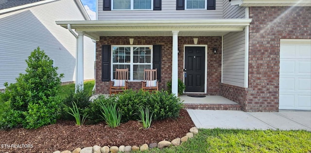 3038 Lazy River Dr, Knoxville, TN 37931 - view of exterior entry with a porch, brick siding, and a garage