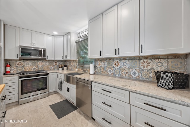 2991 Walden Flats Way, Sevierville, TN 37862 - kitchen with stainless steel appliances, backsplash, white cabinetry, and light stone countertops