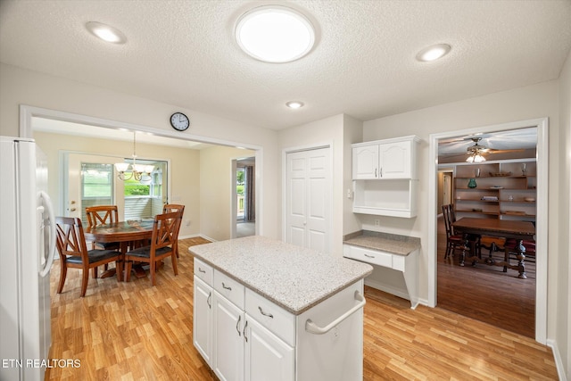 103 Wickham Ln, Fairfield Glade, TN 38558 - kitchen featuring freestanding refrigerator, light wood-style floors, a textured ceiling, white cabinets, and a center island