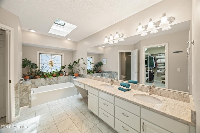 103 Wickham Ln, Fairfield Glade, TN 38558 - bathroom with a skylight, double vanity, a garden tub, a walk in closet, and a textured ceiling