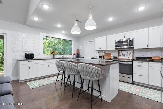 9401 Shirley Ann Rd, Kodak, TN 37764 - kitchen featuring stainless steel appliances, dark countertops, a breakfast bar, backsplash, and recessed lighting
