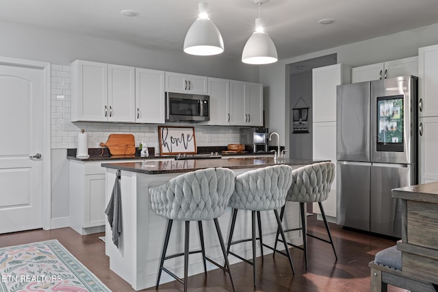 9401 Shirley Ann Rd, Kodak, TN 37764 - kitchen featuring appliances with stainless steel finishes, decorative backsplash, a kitchen breakfast bar, and white cabinetry