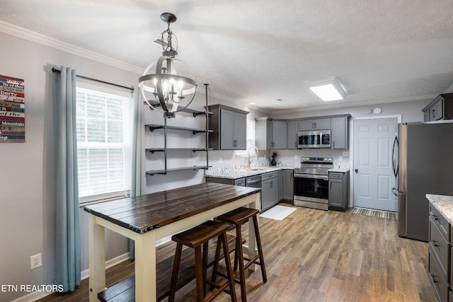 8306 Foxworth Trl, Powell, TN 37849 - kitchen with stainless steel appliances, gray cabinetry, a chandelier, crown molding, and light wood finished floors