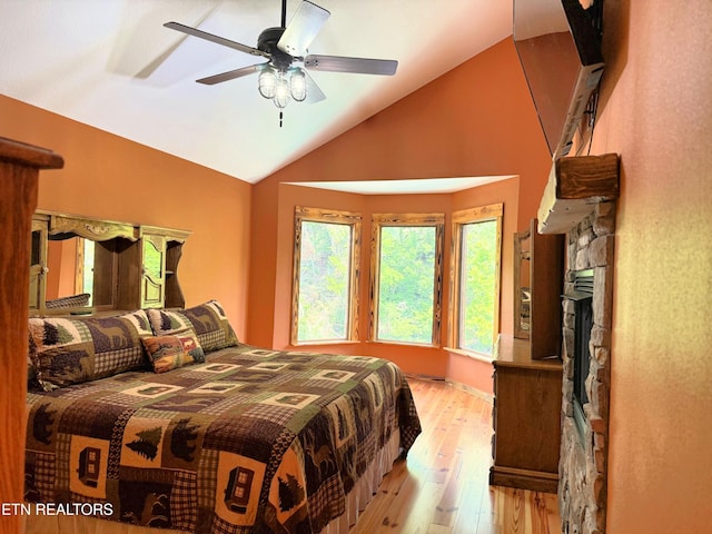 1659 Cherohala Skwy, Tellico Plains, TN 37385 - bedroom with lofted ceiling, light wood-style flooring, a stone fireplace, and a ceiling fan