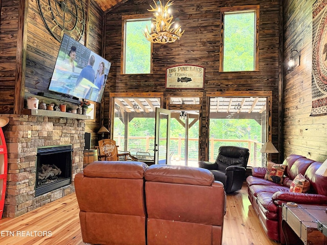 1659 Cherohala Skwy, Tellico Plains, TN 37385 - living room with wooden walls, high vaulted ceiling, hardwood / wood-style floors, a stone fireplace, and a chandelier