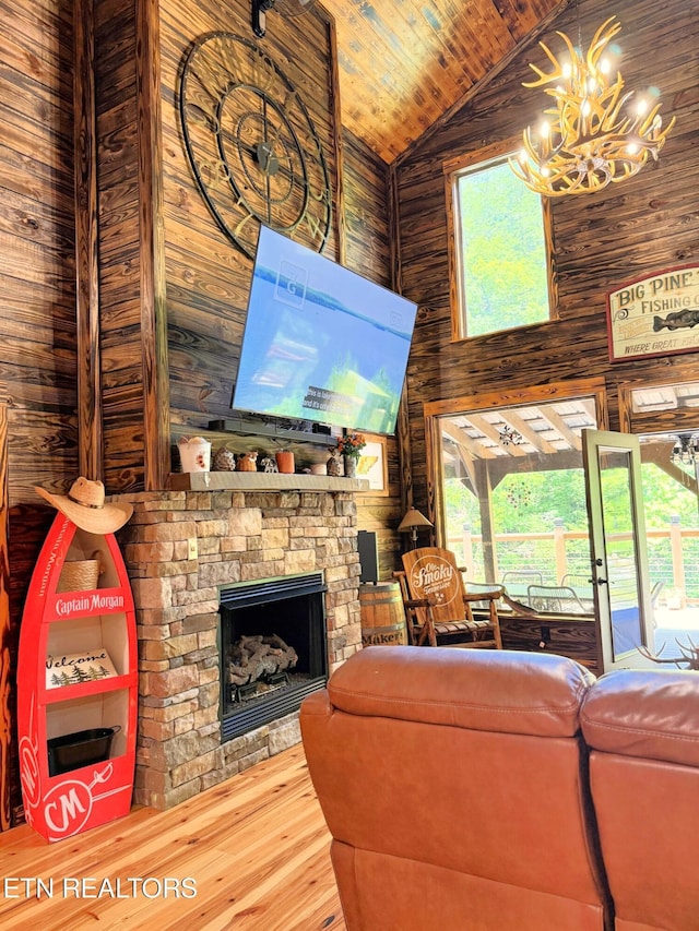 1659 Cherohala Skwy, Tellico Plains, TN 37385 - living room with a chandelier, wood finished floors, wood walls, a stone fireplace, and wooden ceiling
