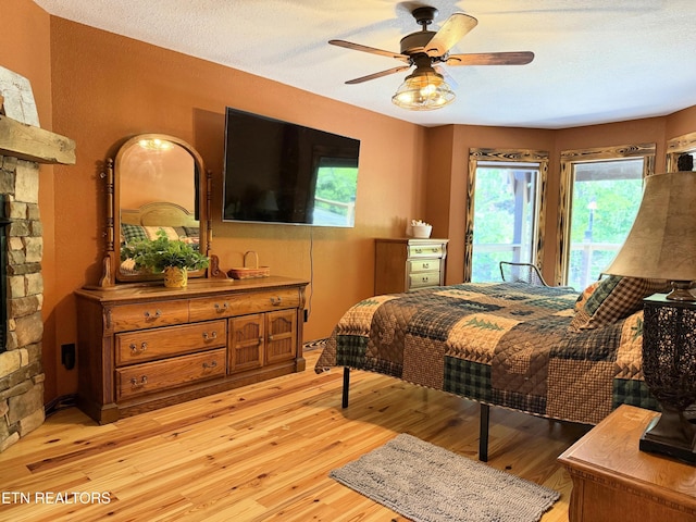 1659 Cherohala Skwy, Tellico Plains, TN 37385 - bedroom with access to exterior, a fireplace, light wood-type flooring, and a ceiling fan