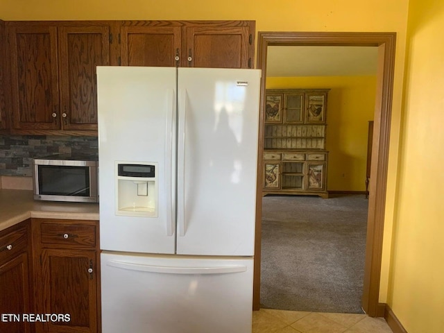 1315 Winchester Ave, Middlesboro, KY 40965 - kitchen with white refrigerator with ice dispenser, stainless steel microwave, light colored carpet, backsplash, and light countertops