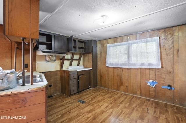 807 E E Chestnut St, Lafollette, TN 37766 - kitchen featuring wood walls, wood finished floors, brown cabinetry, light countertops, and a textured ceiling