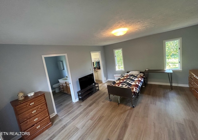 1790 Coon Hunt Rd, Baxter, TN 38544 - bedroom with light wood-style flooring, a textured ceiling, a spacious closet, ensuite bath, and a closet