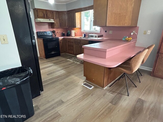 1790 Coon Hunt Rd, Baxter, TN 38544 - kitchen featuring black range with electric stovetop, under cabinet range hood, light wood-style floors, a peninsula, and a kitchen breakfast bar