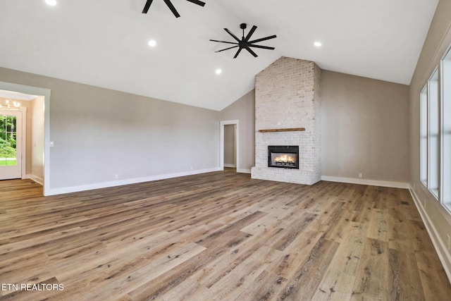 320 Ridge Ln, Monterey, TN 38574 - unfurnished living room with vaulted ceiling, a brick fireplace, wood finished floors, a chandelier, and a ceiling fan