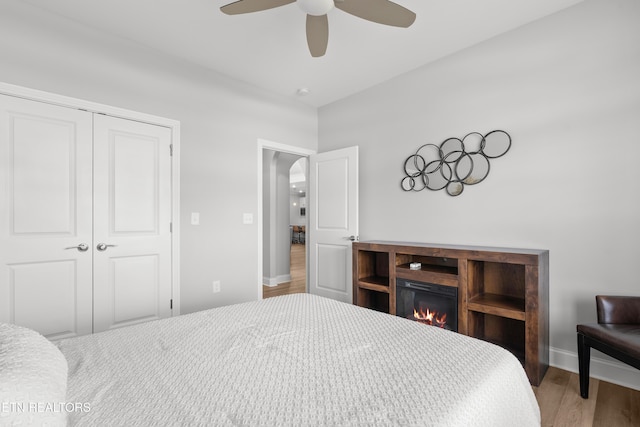 402 Sycamore Pl, Loudon, TN 37774 - bedroom featuring wood finished floors, a closet, arched walkways, ceiling fan, and a lit fireplace
