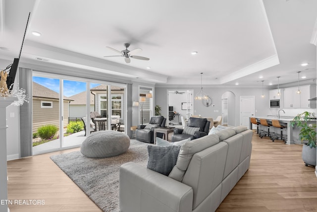 402 Sycamore Pl, Loudon, TN 37774 - living area featuring a tray ceiling, a ceiling fan, light wood-style flooring, arched walkways, and ornamental molding