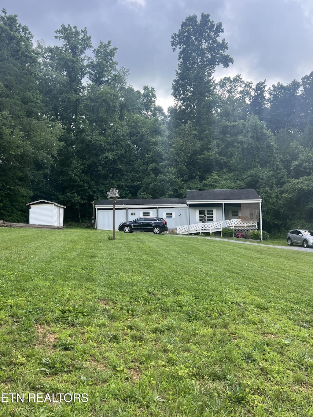 8511 Heiskell Rd, Powell, TN 37849 - view of front of house with a front yard, a view of trees, a storage shed, and a detached garage
