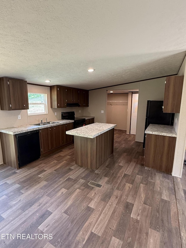 1684 Shields Dr, Morristown, TN 37814 - kitchen featuring black appliances, dark wood-style floors, a kitchen island, a textured ceiling, and light countertops