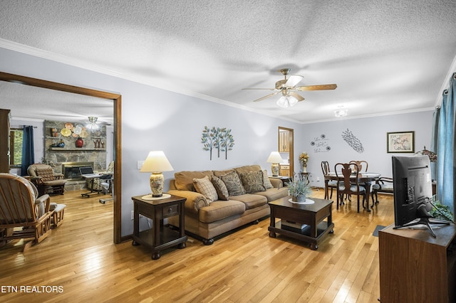 122 Glenwood Dr, Crossville, TN 38555 - living room with ceiling fan, a textured ceiling, light wood-style floors, crown molding, and a stone fireplace
