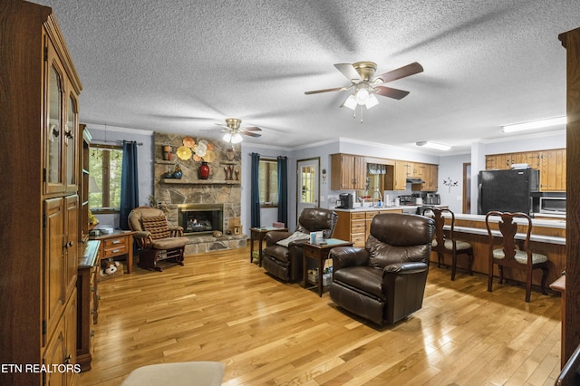 122 Glenwood Dr, Crossville, TN 38555 - living area featuring light wood-style floors, a textured ceiling, a ceiling fan, a fireplace, and ornamental molding