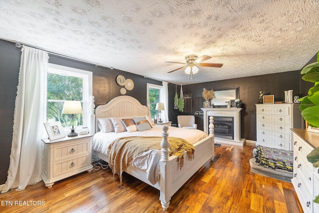 1839 Plumb Creek Cir, Knoxville, TN 37932 - bedroom featuring wood finished floors, a textured ceiling, a fireplace with raised hearth, and a ceiling fan