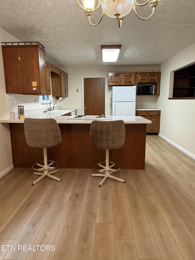 195 Hamblin St, New Tazewell, TN 37825 - kitchen with white appliances, a peninsula, light countertops, a textured ceiling, and brown cabinetry
