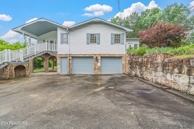 363 Staghorn Ln, Seymour, TN 37865 - view of home's exterior featuring driveway, a garage, stairs, stone siding, and covered porch