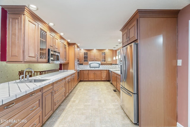 363 Staghorn Ln, Seymour, TN 37865 - kitchen featuring appliances with stainless steel finishes, tile countertops, decorative backsplash, glass insert cabinets, and brown cabinetry