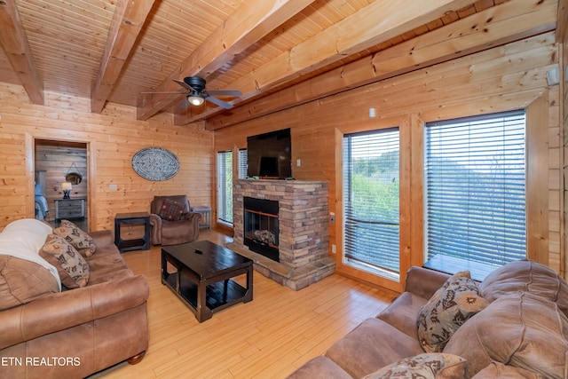 1032 Black Bear Cub Way, Sevierville, TN 37862 - living room featuring wooden walls, a ceiling fan, wood-type flooring, a stone fireplace, and a wooden ceiling with exposed beams