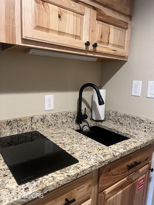 354 E Holly Ridge Rd Unit 354, Gatlinburg, TN 37738 - kitchen view of black electric cooktop, light brown cabinetry, light stone countertops, and a textured wall