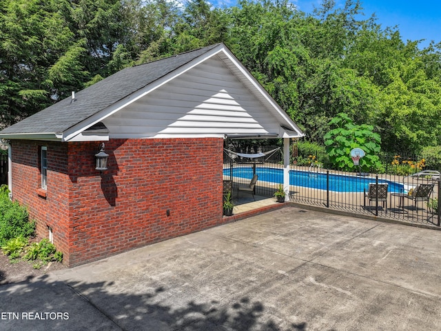 112 Reed Cir, Johnson City, TN 37601 - view of side of property with brick siding, an outdoor pool, roof with shingles, a patio area, and view of wooded area