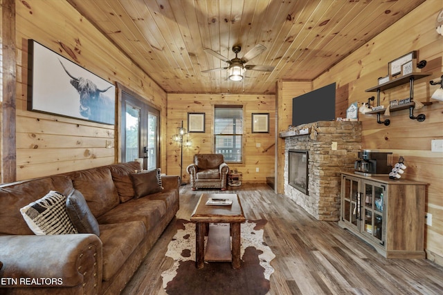 3169 Bear Mountain Ln, Sevierville, TN 37876 - living area with wooden walls, wood finished floors, a stone fireplace, a ceiling fan, and wood ceiling