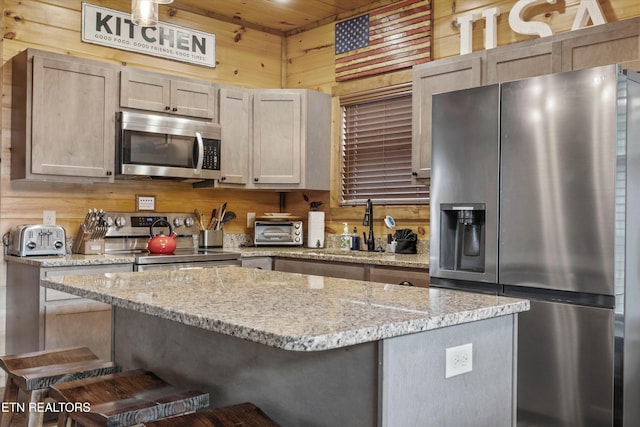3169 Bear Mountain Ln, Sevierville, TN 37876 - kitchen featuring stainless steel appliances, a kitchen breakfast bar, wooden walls, a center island, and light stone countertops
