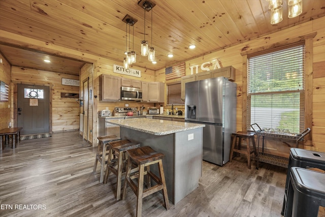 3169 Bear Mountain Ln, Sevierville, TN 37876 - kitchen with stainless steel appliances, wooden walls, wood finished floors, a kitchen island, and healthy amount of natural light