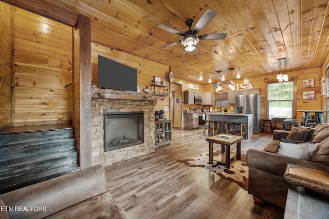 3169 Bear Mountain Ln, Sevierville, TN 37876 - living area featuring wood walls, wood ceiling, light wood-style flooring, a ceiling fan, and a stone fireplace