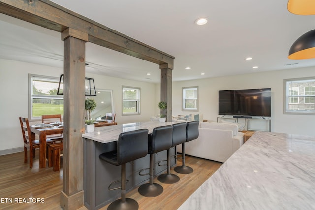 713 Concord Rd, Knoxville, TN 37934 - kitchen with wood finished floors, recessed lighting, light stone countertops, a breakfast bar area, and decorative columns