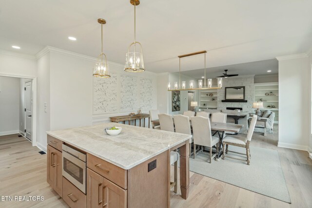 1100 Regality Way, Knoxville, TN 37923 - kitchen with stainless steel microwave, ornamental molding, a center island, light wood-type flooring, and a ceiling fan