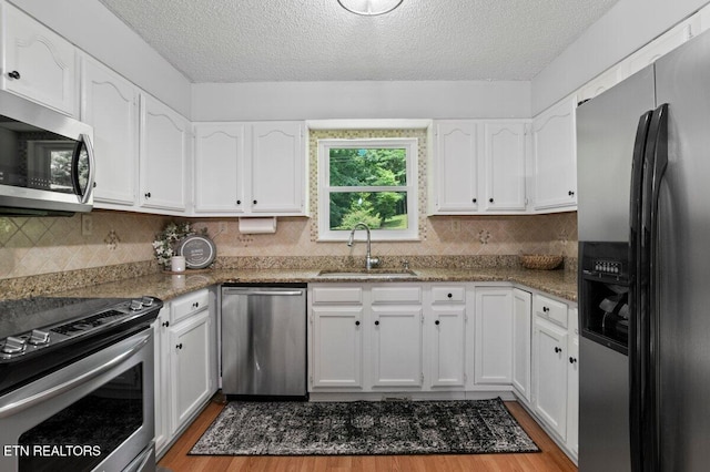 382 Tionesta Dr, Jacksboro, TN 37757 - kitchen featuring stainless steel appliances, white cabinetry, wood finished floors, a textured ceiling, and decorative backsplash