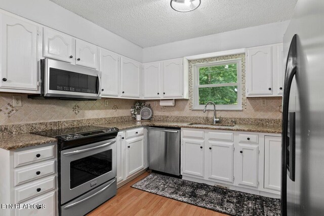 382 Tionesta Dr, Jacksboro, TN 37757 - kitchen with appliances with stainless steel finishes, light wood-style floors, a textured ceiling, white cabinetry, and decorative backsplash
