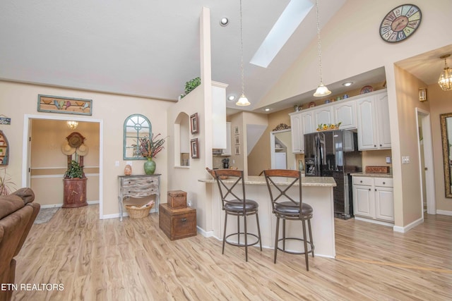 127 Kiowa Way, Loudon, TN 37774 - kitchen with black fridge, light wood-type flooring, a breakfast bar area, a skylight, and high vaulted ceiling