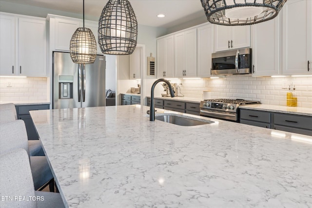 1682 Hickory Reserve Rd, Knoxville, TN 37932 - kitchen with stainless steel appliances, a chandelier, backsplash, light stone countertops, and a kitchen breakfast bar
