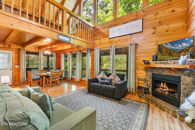 2217 Red Bud Rd, Sevierville, TN 37876 - living room with healthy amount of natural light, wooden walls, hardwood / wood-style floors, a stone fireplace, and a wooden ceiling with exposed beams