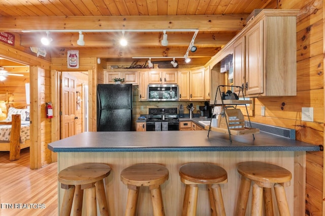 2217 Red Bud Rd, Sevierville, TN 37876 - kitchen with black appliances, track lighting, light brown cabinetry, wood walls, and light wood-style flooring