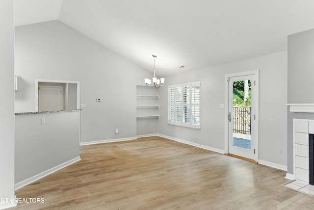 8808 Cedar Springs Ln, Knoxville, TN 37923 - unfurnished dining area with a chandelier, vaulted ceiling, light wood-style floors, built in shelves, and a tiled fireplace